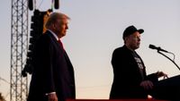 two men stand on a stage behind microphones