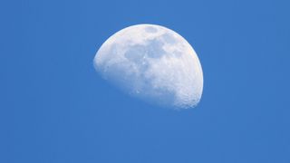 the moon seen in a bright blue sky